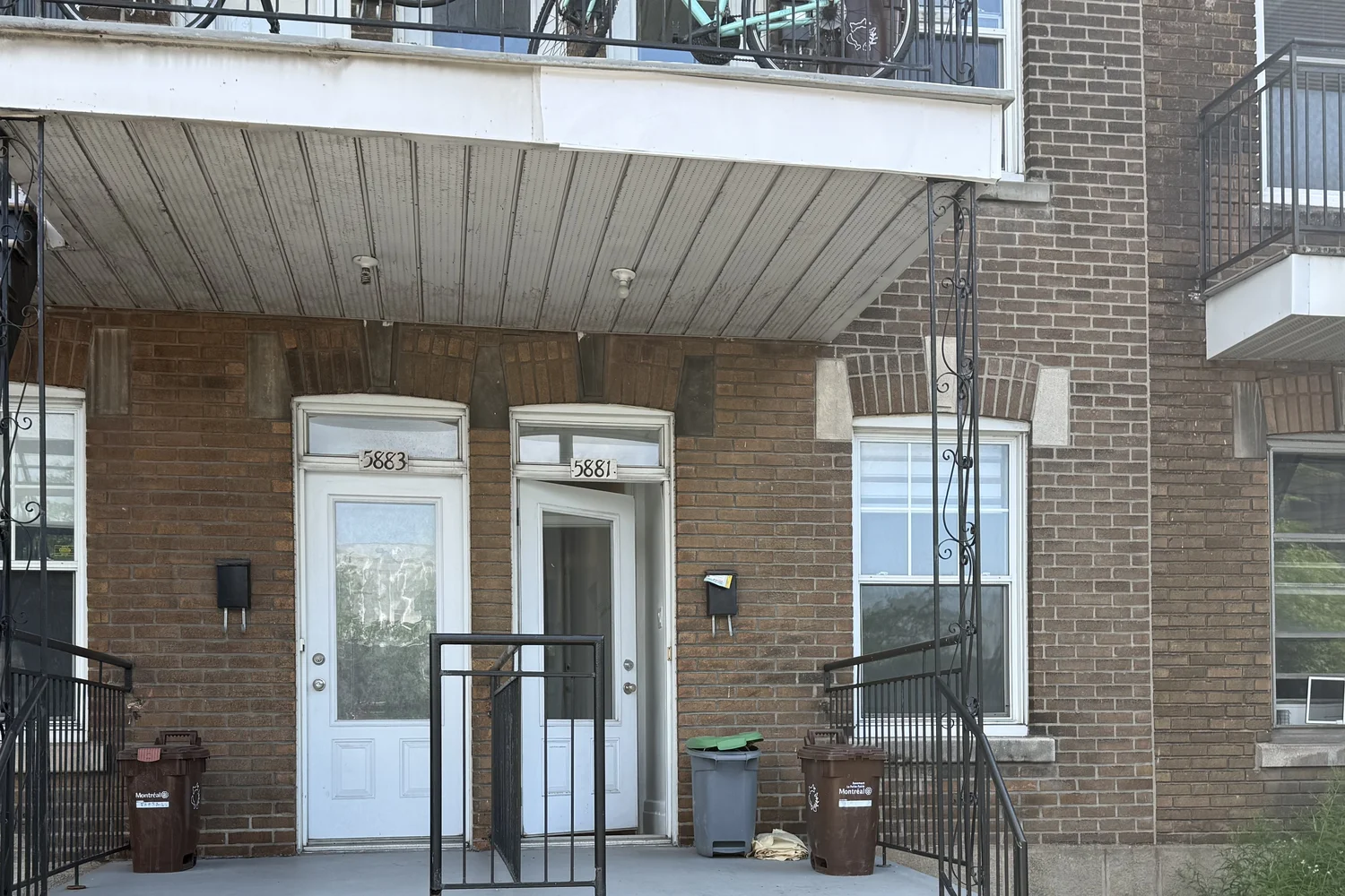 Le triplex vu de la rue, avec les immeubles voisins en brique.