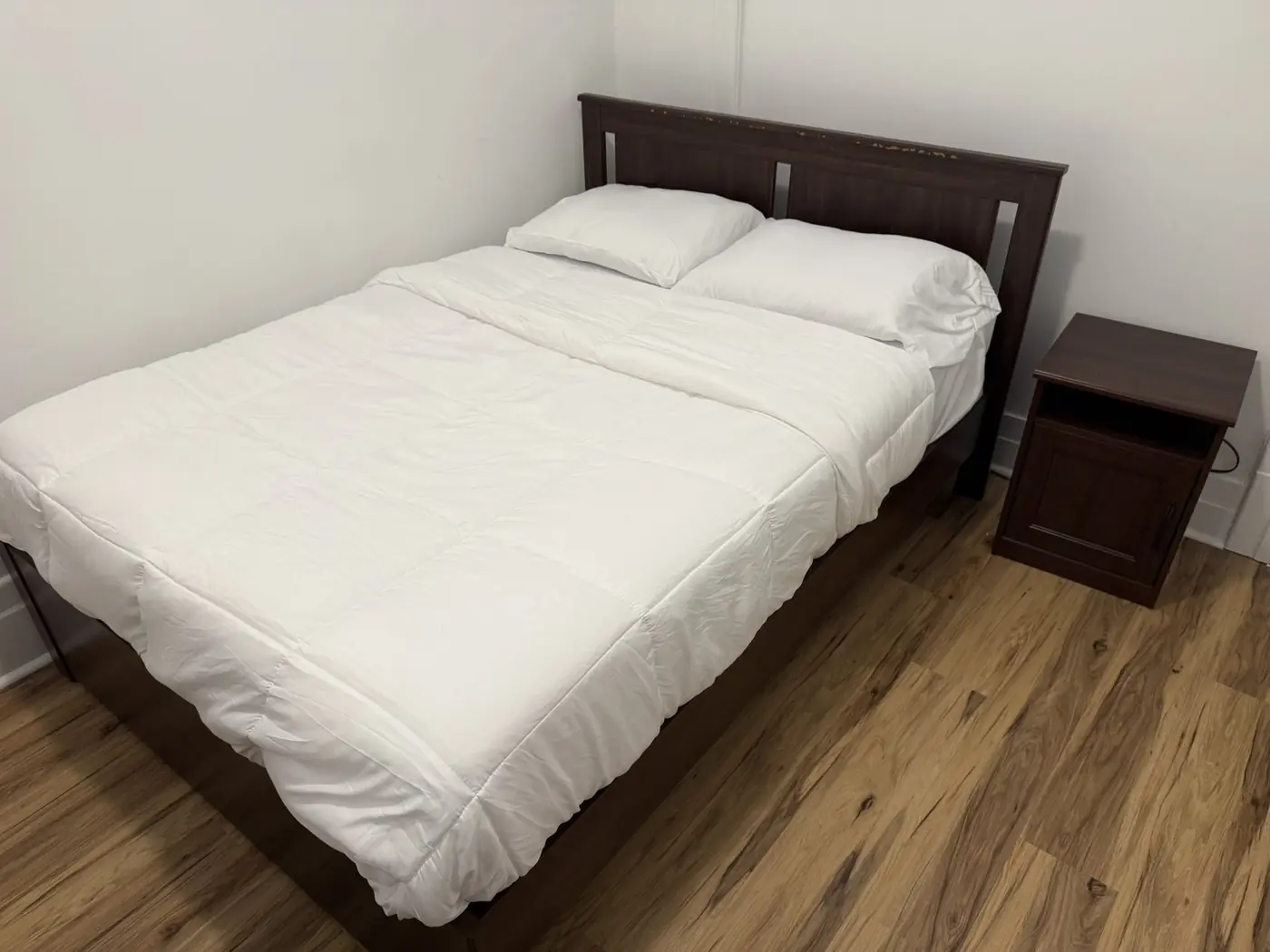 Chambre meublée avec lit double et plancher de bois.